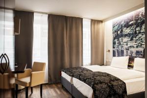 Cette chambre comprend un lit, un bureau et une fenêtre. dans l'établissement Helvetia Hotel Munich City Center, à Munich