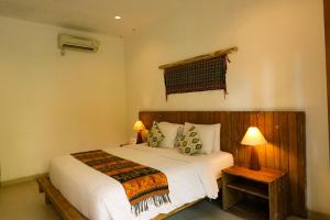 a bedroom with a bed with white sheets and pillows at Mina Pelasa Hotel in Legian