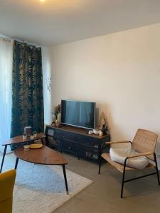 a living room with a flat screen tv and two chairs at Appartement charmant à 10 minutes des plages in Châteauneuf-lès-Martigues +18 photos