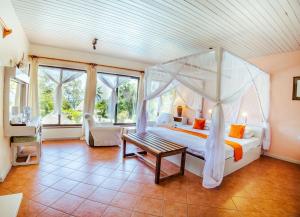 1 dormitorio con cama con dosel y mesa en Flamboyant Diani Beach en Diani Beach