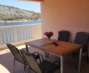 a wooden table with chairs and a vase of flowers on a balcony at Apartments by the sea Razanj, Rogoznica - 2970 in Rogoznica