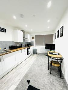 a kitchen with white cabinets and a table in it at 202 Grosvenor House in Wakefield