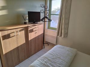 a bedroom with a bed and a tv and a window at Holiday Home Nieuwendamme in Nieuwpoort