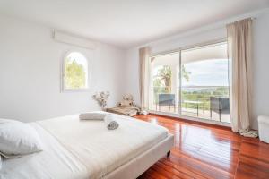 a white bedroom with a large bed and a large window at Villa vue mer et pinède in Bandol