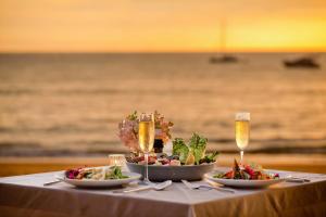 a table with two plates of food and champagne glasses at Le Méridien Phuket Mai Khao Beach Resort in Mai Khao Beach