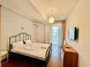 a bedroom with a bed and a tv on a wall at Catalina Summerland Apartaments Mamaia Nord in Mamaia