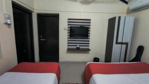 Habitación con 2 camas y TV en la pared. en Samarth Resort, en Bhurkīā
