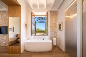 uma banheira na casa de banho com uma janela em Es Figueral Nou Hotel Rural & Spa - Adults Only - Over 12 em Montuiri