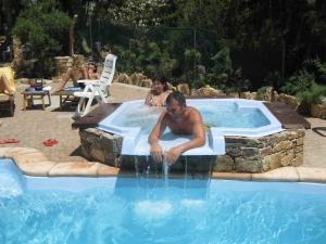 Un uomo seduto in una piscina con acqua che esce di Hotel Villa Belfiori a Torre Dei Corsari