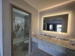 a bathroom with a sink and a tub and a mirror at Days Inn by Wyndham El Paso Airport East in El Paso