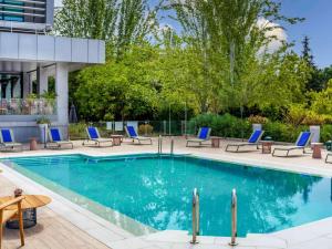 a swimming pool with blue chairs and a table at Novotel Madrid City Las Ventas in Madrid