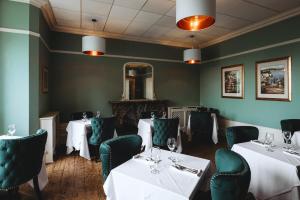 Millfields Hotel في غريمسبي: غرفة طعام مع طاولات وكراسي ومرآة