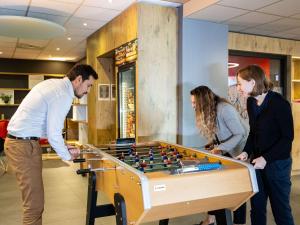 un grupo de personas de pie alrededor de una mesa de futbolín en ibis Bordeaux Centre Meriadeck en Burdeos