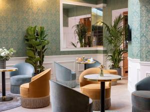 een restaurant met tafels, stoelen en planten bij Hotel Mercure La Sorbonne Saint-Germain-des-Prés in Parijs