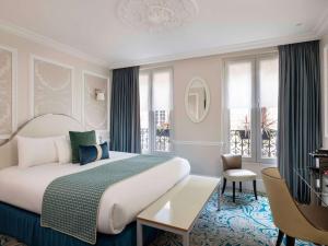 a hotel room with a bed and a desk and windows at Hotel Mercure La Sorbonne Saint-Germain-des-Prés in Paris