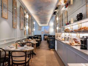 パリにあるホテル メルキュール ラ ソルボンヌ サンジェルマン デ プレのテーブルと椅子のあるレストラン、バー