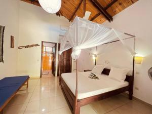 1 dormitorio con 1 cama blanca con sombrilla en Résidence Kambana, en Nosy Be