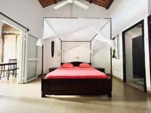a bedroom with a canopy bed with red sheets at Résidence Kambana in Nosy Be
