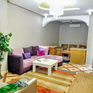 sala de estar con sofá púrpura y mesa en 2 bedrooms apartement with city view and garden at Fes, en Fez