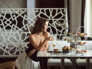 拉巴特的住宿－拉巴特索菲特玫瑰園酒店，坐在餐桌上吃一盘食物的女人