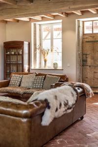 a dog laying on a leather couch in a living room at La Ferme du Domaine de Bassol - Piscine & Billard in Mézériat