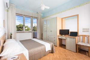 a bedroom with a bed and a desk and a television at Hotel Meeting in Cesenatico