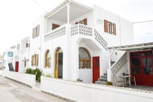 a white building with red doors on a street at Asteri Hotel in Ornos