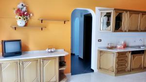 uma cozinha com armários de madeira e uma televisão na parede em 2 bedrooms apartement with city view at Avola 1 km away from the beach em Avola