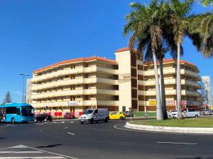 een groot gebouw met auto's geparkeerd op een parkeerplaats bij Tanife 310 - Playa del Ingles comfort Suite with Sunset view in Playa del Inglés