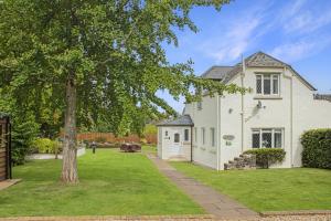 a white house with a tree in the yard at Plum Tree Cottage, Porlock in Porlock
