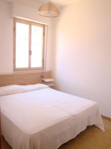 białe łóżko w pokoju z oknem w obiekcie Cala Vigliena Il Sole Negli Occhi w mieście Punta Braccetto