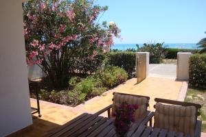 zwei Bänke auf einer Terrasse mit rosa Blumen in der Unterkunft Cala Vigliena Il Sole Negli Occhi in Punta Braccetto