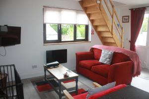 a living room with a red couch and a tv at The Lodge in Newcastle Emlyn