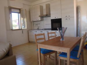 eine Küche und ein Esszimmer mit einem Holztisch und Stühlen in der Unterkunft Cala Vigliena Il Sole Negli Occhi in Punta Braccetto