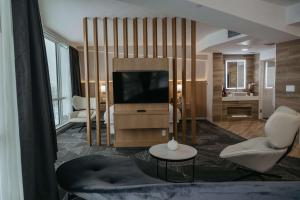 ein Wohnzimmer mit einem TV, einem Sofa und einem Tisch in der Unterkunft Clarion Lakeside Inn & Conference Centre in Kenora