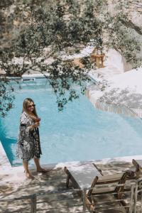 a woman standing in front of a swimming pool at Zos Suites in Kanakis