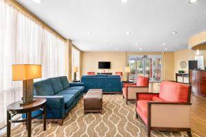 a living room with a blue couch and red chairs at Comfort Suites Orlando Airport in Orlando