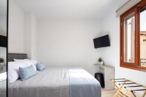 een witte slaapkamer met een bed en een raam bij Ebenus Residence in Rethimnon
