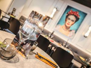 a table with glasses and a picture of a woman at Ibis Styles Clermont-Ferrand République in Clermont-Ferrand