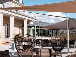 - un ensemble de chaises sous un parasol sur une terrasse dans l'établissement Mercure Chantilly Resort & Conventions, à Chantilly