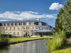 een groot gebouw met een rivier ervoor bij Mercure Chantilly Resort & Conventions in Chantilly
