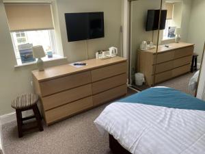 um quarto com uma cama e uma cómoda com uma televisão em The Strathearn Hotel em Fife