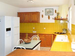 Saint-Paul-en-ForêtにあるHoliday Home Maison Bleue by Interhomeのキッチン(木製キャビネット、白い冷蔵庫付)