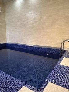 een zwembad in een badkamer met blauwe tegels bij شاليهات توليب in Al Falt