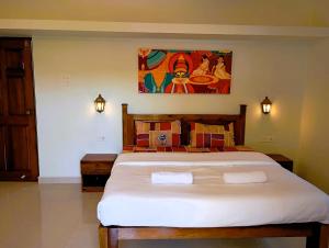ein Schlafzimmer mit einem großen Bett und einem Gemälde an der Wand in der Unterkunft Cielo in Palolem