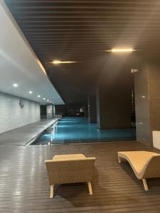 a swimming pool with two benches in a building at DeAr Caspian Grand Sunkono Lagoon Apartment in Surabaya