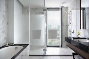 a bathroom with a shower and a tub and a sink at The David Kempinski Tel Aviv in Tel Aviv