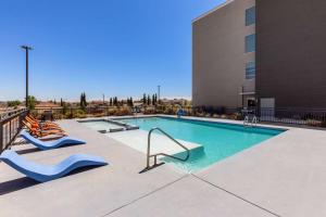 einem Pool mit zwei Liegestühlen und einem Gebäude in der Unterkunft La Quinta Inn & Suites by Wyndham El Paso East Loop-375 in El Paso