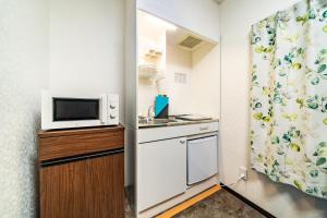 a small kitchen with a microwave and a refrigerator at 84-5, Shiomi 301, Entire room for rent in Tokyo