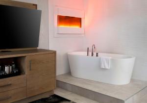 DoubleTree by Hilton Poughkeepsie في باوكيبسي: حمام مع حوض استحمام وتلفزيون